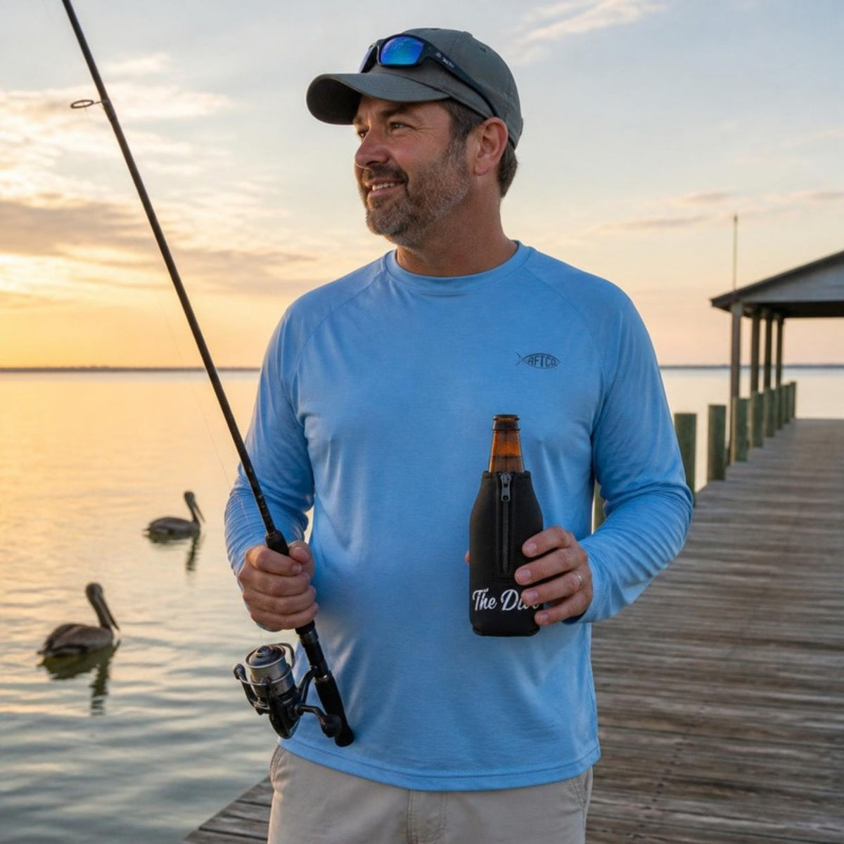 Man fishing off a pier with The Dive bottle koozie
