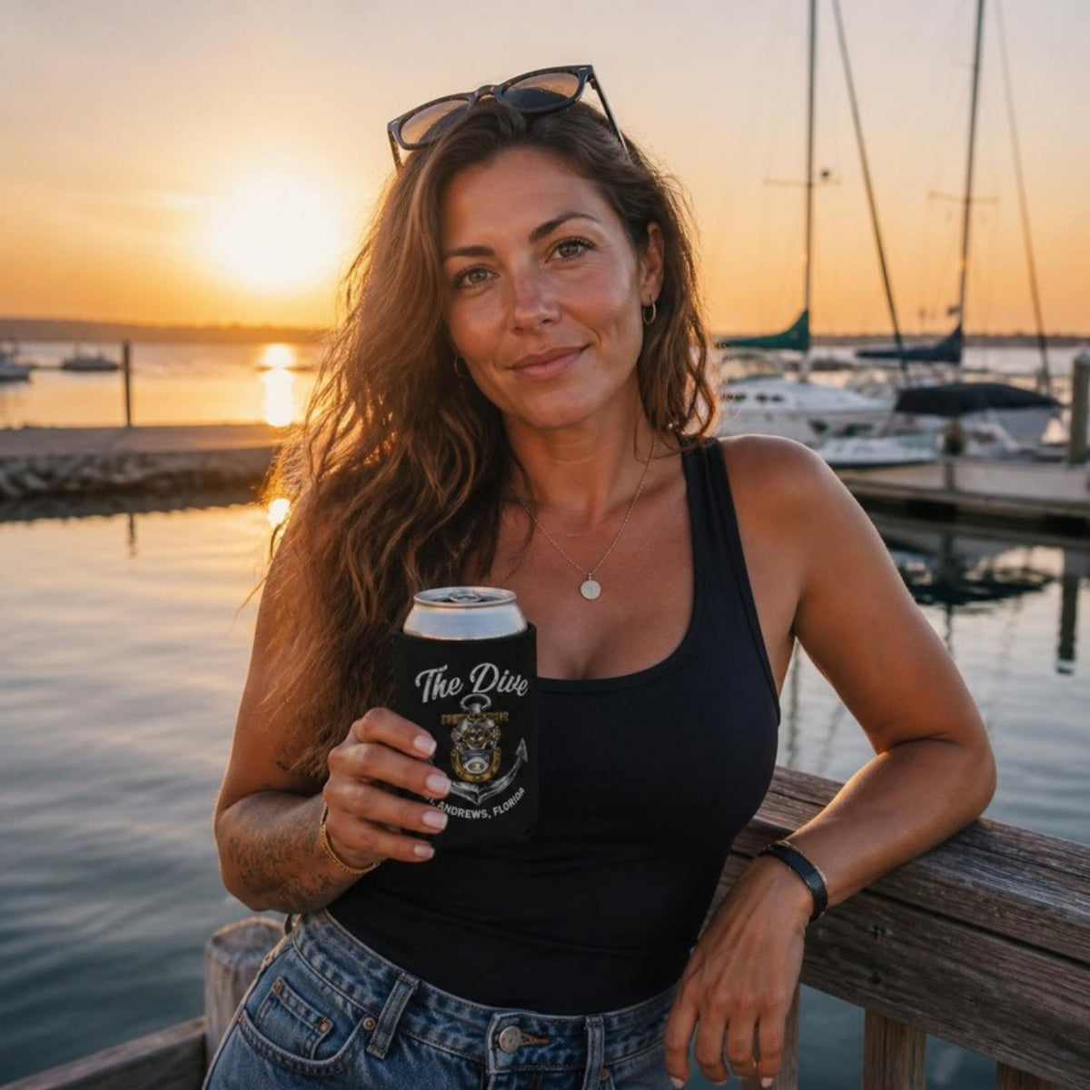 Woman at a marina at sunset with The Dive can koozie