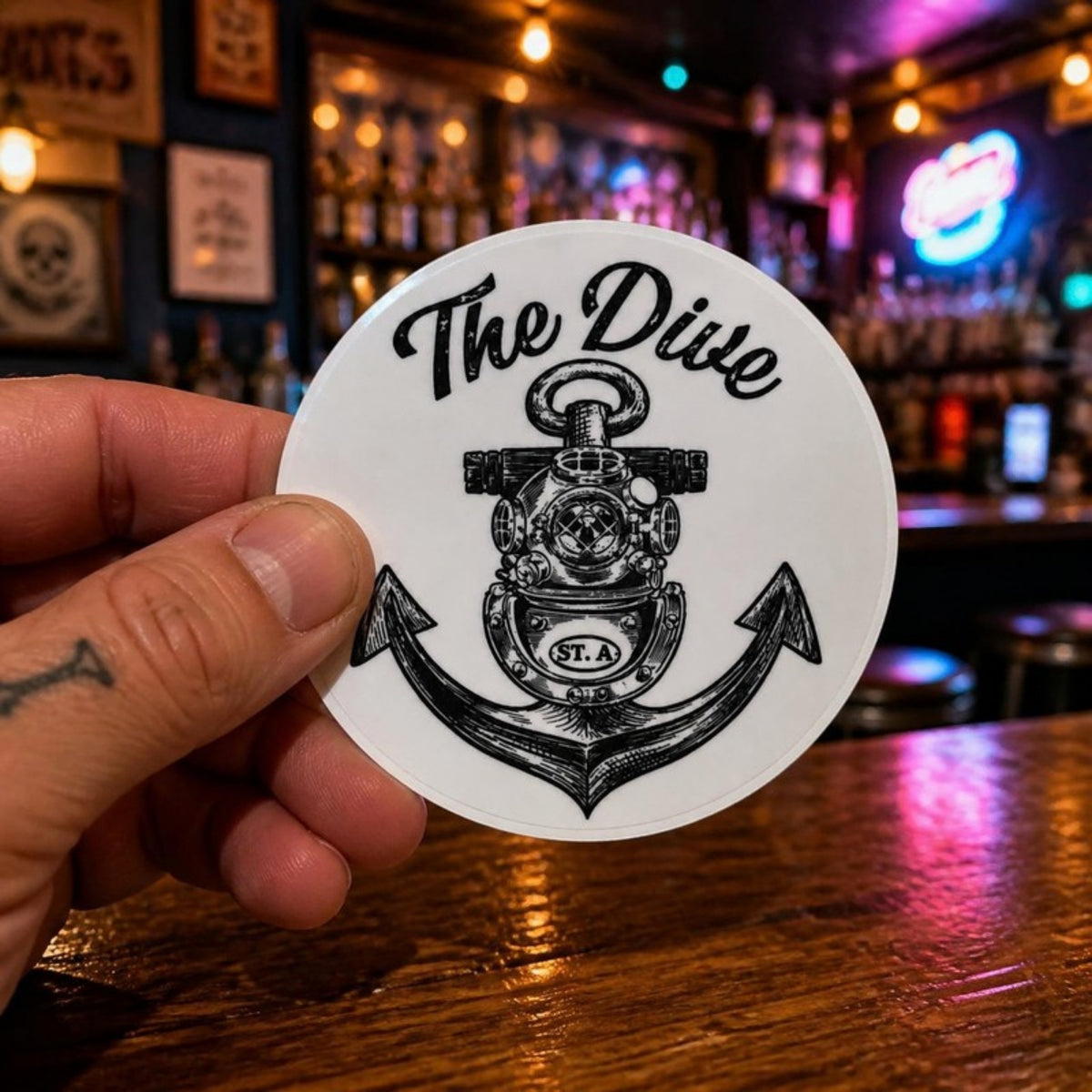 Holding The Dive round sticker in the bar