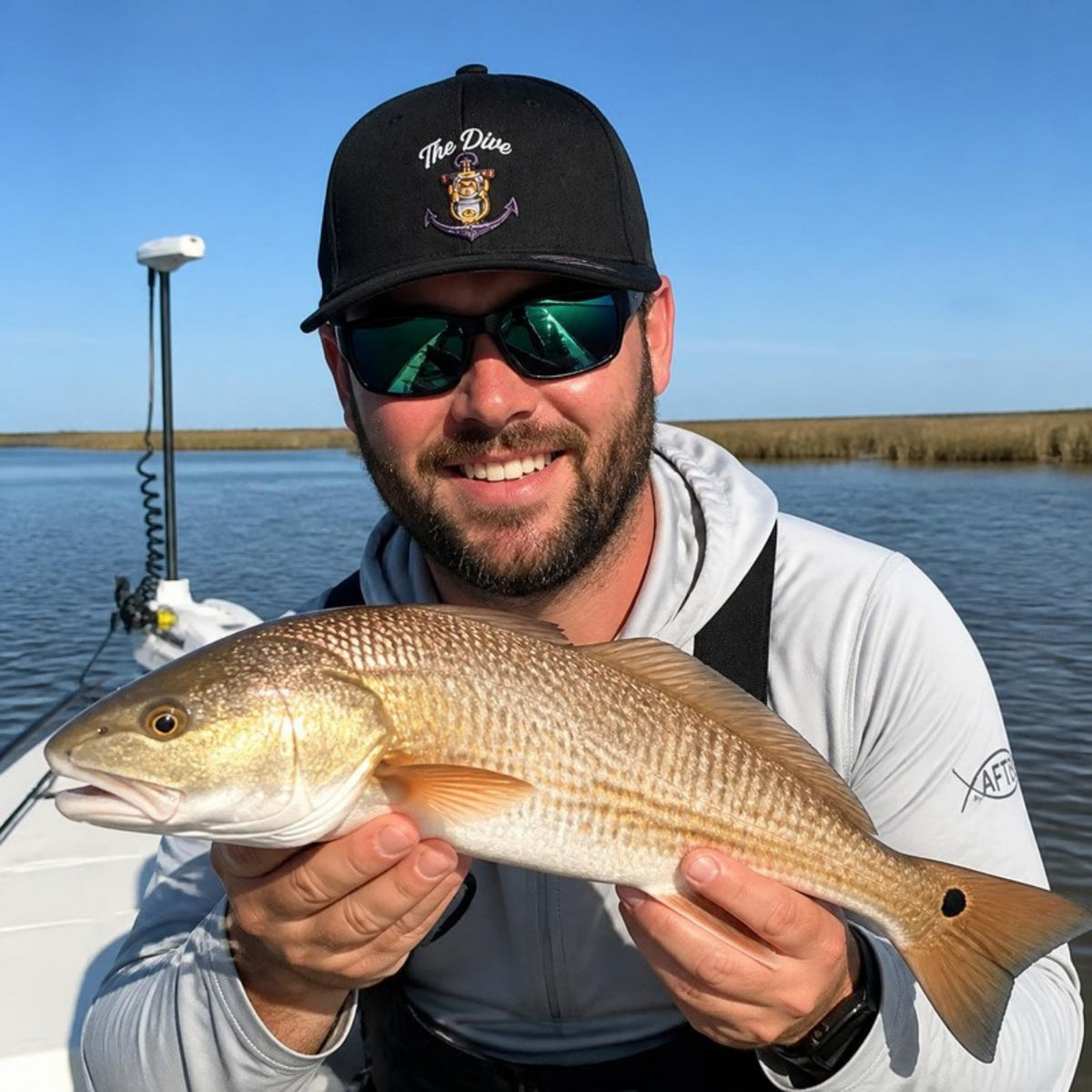 Man wearing The Dive hat holding a redfish