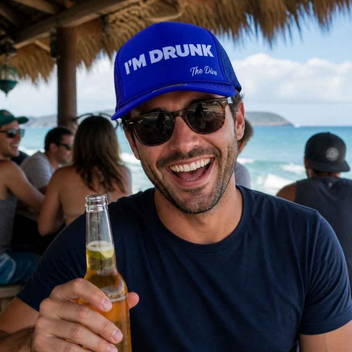 Man at a beach bar wearing the blue I Am RUNK hat