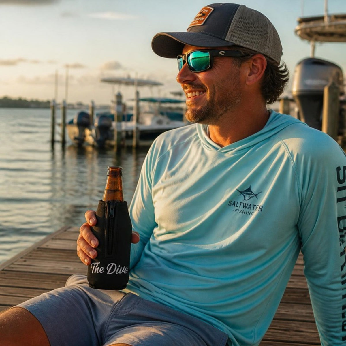 Man on a marina dock holding a beer in The Dive bottle koozie